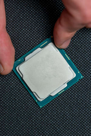 Fingers holding cpu microchip on black background. Micro photography, top view.の写真素材