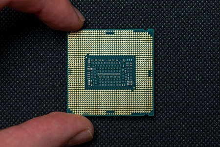 Fingers holding cpu microchip on black background. Micro photography, top view.の写真素材