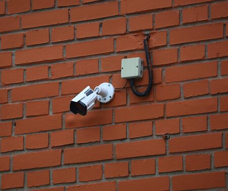 Surveillance camera on the red brick wall