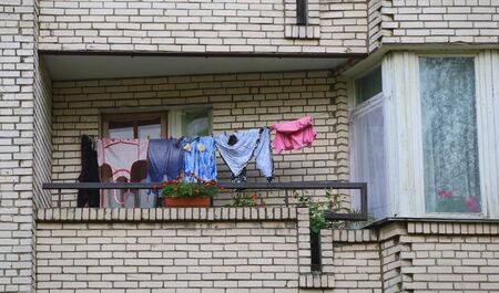 Linen and clothes hung after washing to dry on the balcony of a brick houseの写真素材