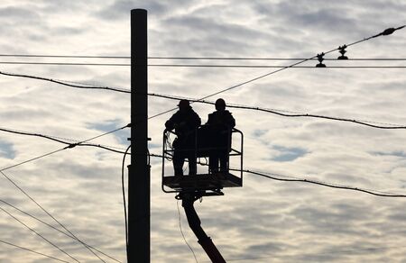 Installers Working on high-altitude workers with cables at height on a background cloudy skyの写真素材