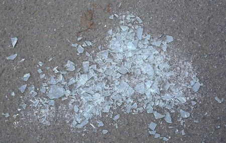 Shards of broken glass on the gray asphalt