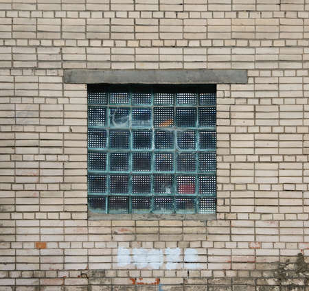 A window made of glass blocks in a white brick wallの写真素材