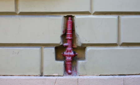 Red fire hydrant in the wall of the houseの写真素材