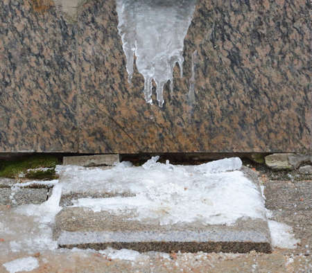 Melting spring icicle on a granite wallの写真素材