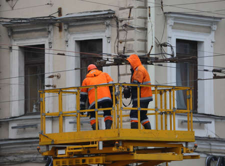 Two electrical workers in orange uniforms at workの写真素材