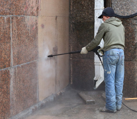 A cleaning worker washes the granite wall of a house with professional equipment, Nevsky Prospekt, Saint Petersburg, Russia, April 2021のeditorial素材