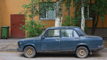 An old blue Soviet car in the courtyard of a residential building