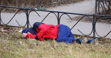 A drunken tramp in sportswear sleeps on the lawn, ulitsa podvoyskogo, Saint Petersburg, Russia,...