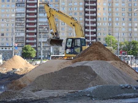 Excavator among saws of sand on construction in the middle of a city street, ulitsa Kollontai, Saint Petersburg, Russia, August 2021のeditorial素材