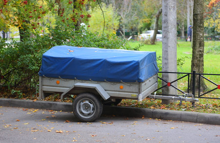 A small two-wheeled gray car trailer is covered with a blue awning