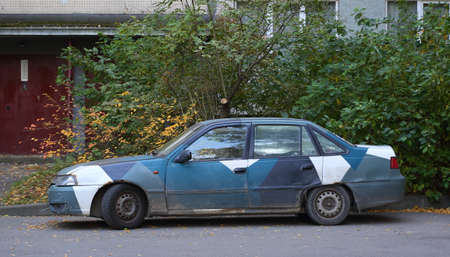 An old multicolored car at the entrance to a residential buildingの写真素材