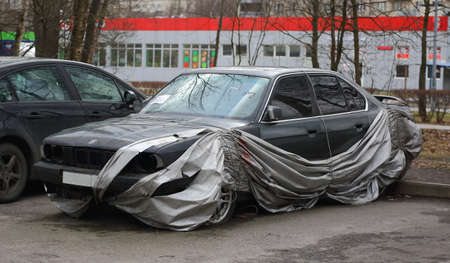 A broken car after an accident in a Parking lot covered with a slid coverの写真素材