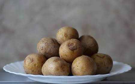 Boiled potatoes in the peel on a white plateの写真素材