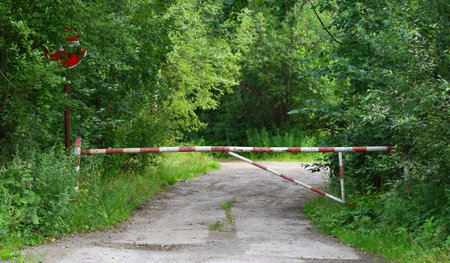 Red and white striped metal barrier on a country road