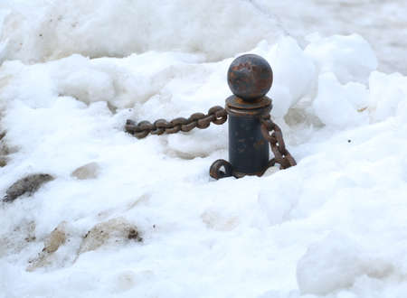 Snow-covered black cast-iron fence with chains