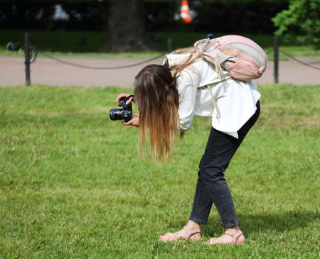 Long-haired girl photographer on the grass of the parkの写真素材