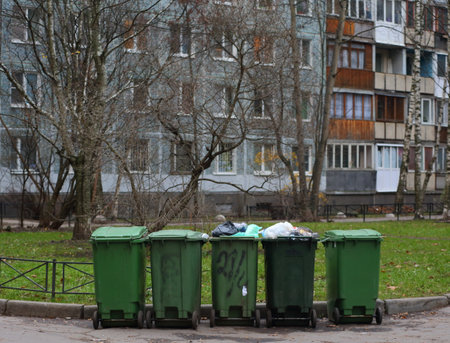 Green plastic mobile containers with garbage in the courtyard of a residential buildingの写真素材