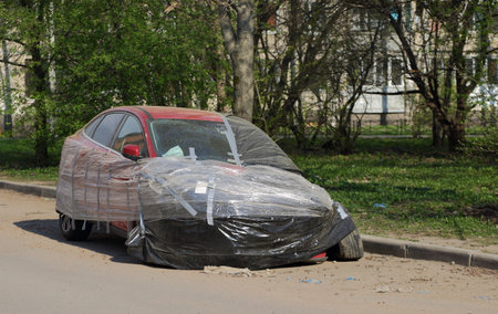 A red broken car is covered with a transparent film after an accidentの写真素材