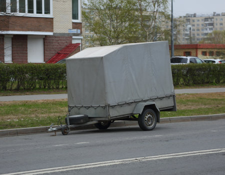 Large two-wheeled gray awning trailer for a passenger car parked on the streetの写真素材