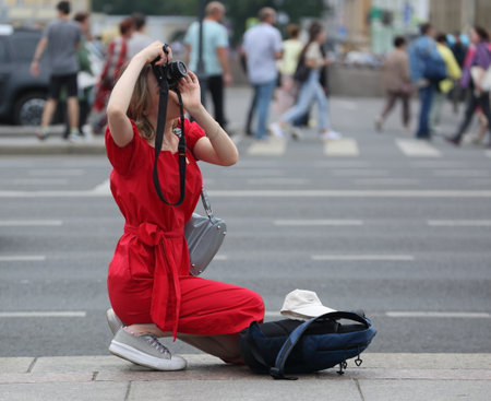 Blonde girl photographer in a red dress on the streetの写真素材