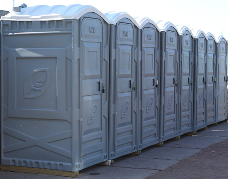 A row of gray plastic mobile toilets with closed doorsの写真素材