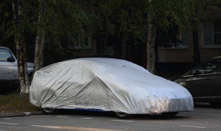 The car in the parking lot is covered with a silver coverの写真素材