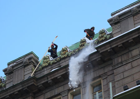 Two municipal workers dump snow from the roof of a building, Nevsky Prospekt, St. Petersburg, Russia, December 06, 2023のeditorial素材