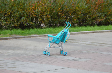 A baby stroller is left on the sidewalk by the lawnの写真素材