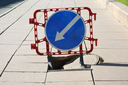 A plastic barrier with a road sign warns of a sewer failure and the need to bypassの写真素材