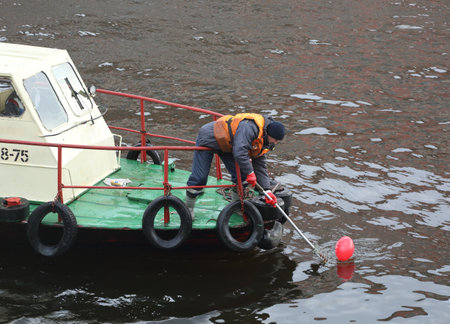 A municipal worker removes debris from the surface of the riverの写真素材