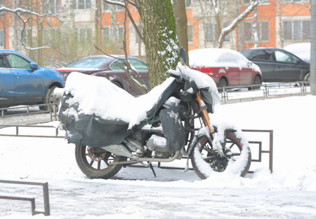 A snow-covered black motorcycle on the streetの写真素材