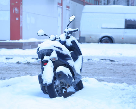A snow-covered black motorcycle on the streetの写真素材