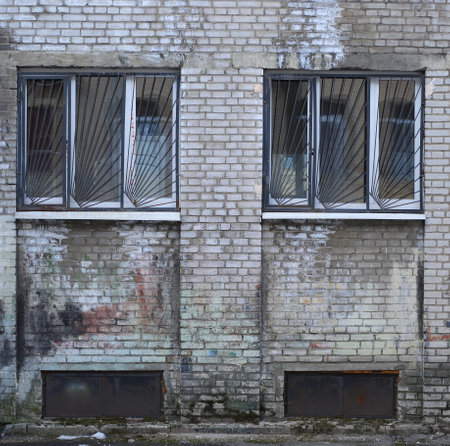 A barred windows in an old gray brick wall