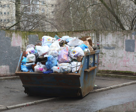 A large dumpster filled with waste in the courtyard of an apartment building