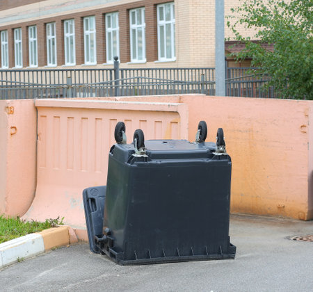 There is an inverted black plastic container by the pink wall of the waste placeの写真素材