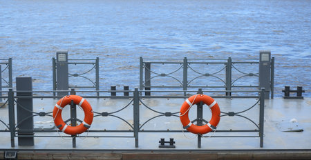 A red lifebuoys hang on the fence of the river pierの写真素材