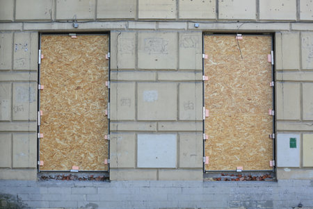 Two windows in the wall of the building are covered with chipboardの写真素材