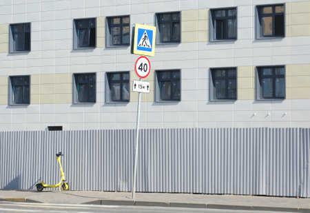 A scooter stands near a metal fence surrounding a building under constructionの写真素材