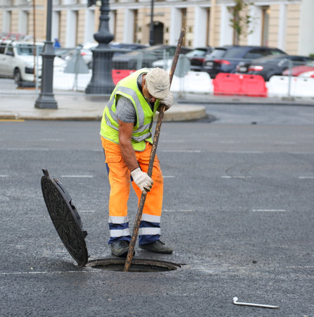 A road worker cleans a manhole from dirt