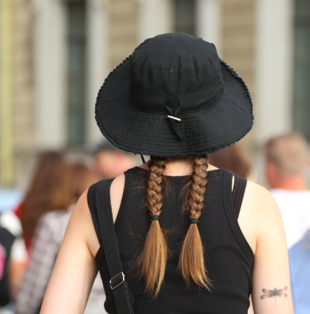 Two pigtails are visible under the black panama hatの写真素材