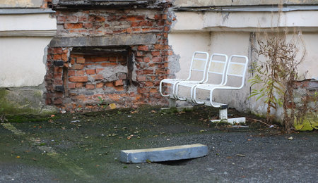 A white metal bench stands near an old brick wallの写真素材