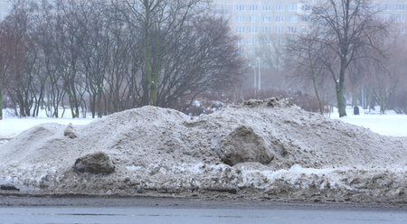 A pile of snow has accumulated on the side of the road as a result of snow removal