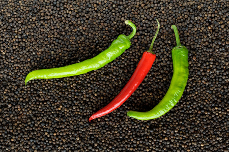 closeup green and red peppers on black peppercorns