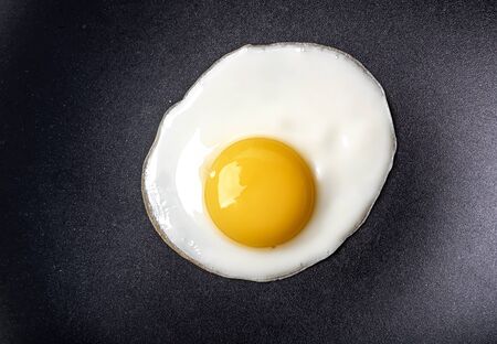 Close-up photo of fried egg on the pan surfaceの写真素材