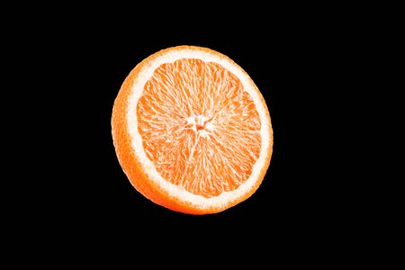 Macro photo of slice of orange fruit isolated on black backgroundの写真素材