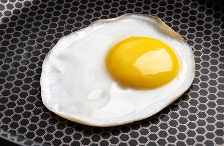 Closeup photo of fried egg on the pan surfaceの写真素材