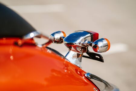 Closeup chrome detail and taillight and turn signals of orange retro vintage scooter