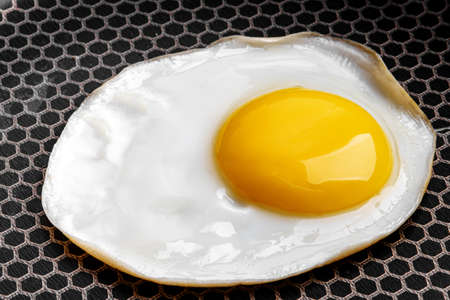 Closeup photo of fried egg on the pan surfaceの写真素材