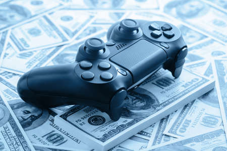 Concept of gaming addiction. Close up photo of gamepad on the money background.